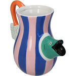 Farverig vase med striber i rosa og blå og med fiskekrop, der stikker ud fra vasen - Den ligner en kande, men den er skabt til blomster og dekoration.