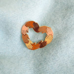 Hjerteformet pin-nål, som fejrer skønheden og mangfoldigheden i vores verden.  Hånd i hånd - Fred og kærlighed på denne jord!