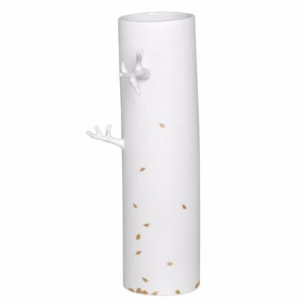 Høj og slank vase i hvid porcelæn med dekorative grene stikkende ud fra vasen og faldende løv i form af små guldblade.